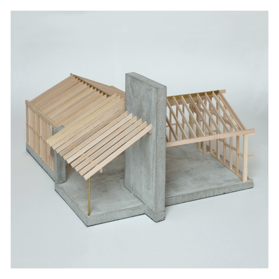 Model of a building structure featuring a gray concrete wall and wooden frame sections, including slanted roof panels. The design resembles an unfinished open-concept architectural layout.