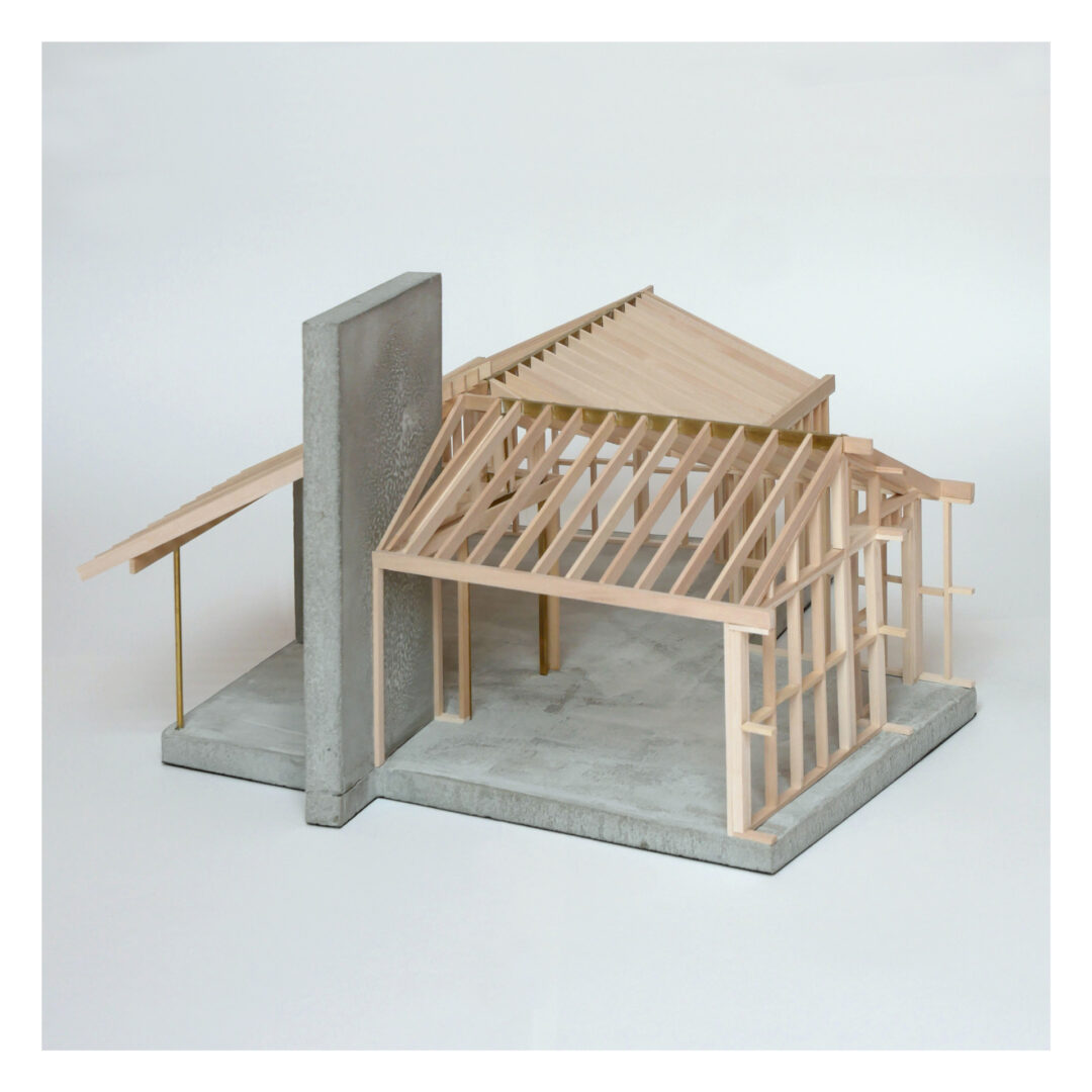 A scale model of a building under construction, featuring a concrete wall and a wooden frame structure. The model is set on a plain white background, highlighting the intricate framework and architectural design elements.