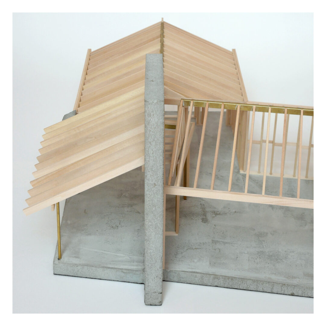 A detailed architectural model showcasing part of a building structure. It features a concrete base, a wooden roof with visible rafters, and a partially constructed open wooden frame.