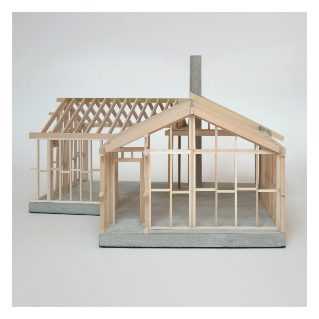 An architectural model of a single storey house made from wooden slats on a concrete base. The model showcases the exposed framework of the building, highlighting the roof trusses and vertical studs against a plain background.
